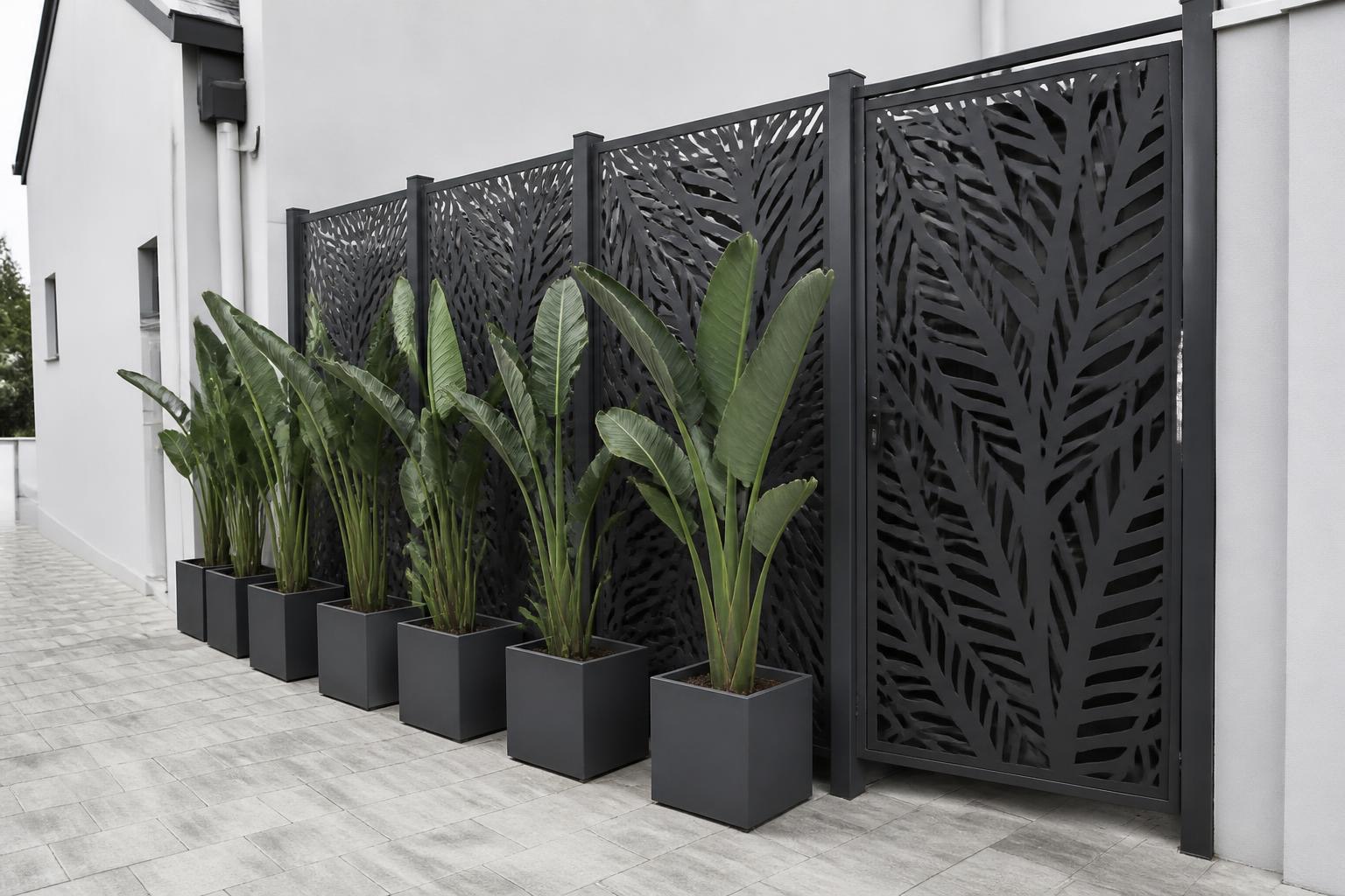 Black laser-cut leaf-pattern privacy screens with potted plants